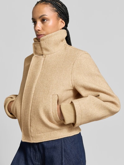 Frauenmodel trägt Bomberjacke aus Woll-Mix von Victoria Beckham in Beige mit Stehkragen, elastischen Ärmelabschlüssen, Eingrifftaschen, Ganzkörperansicht von vorne.
