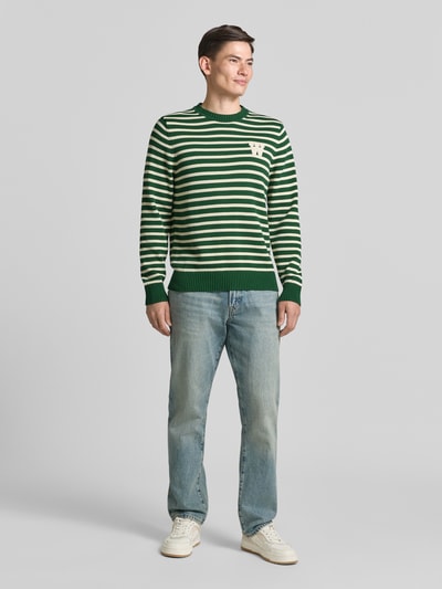 Männermodel trägt Strickpullover mit Rundhalsausschnitt von Wood Wood in Grün-Weiß, Reine Baumwolle, Gerader-Schnitt, Label-Stitching, Ganzkörperansicht von vorne