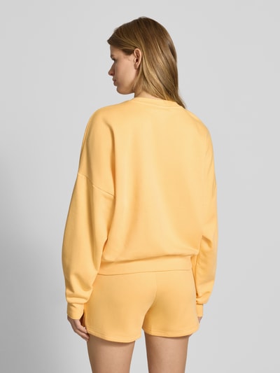 Frauenmodel trägt Sweatshirt mit Logo und Rundhalsausschnitt von adidas Sportswear in Hellgelb, Relaxed Fit, Baumwoll-Mix, Ganzkörperansicht Rückansicht.