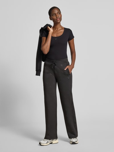 Frauenmodel trägt Slim Fit T-Shirt mit Logo-Applikation von Guess aus elastischem Baumwoll-Mix, Rundhalsausschnitt, Ganzkörperansicht von vorne.