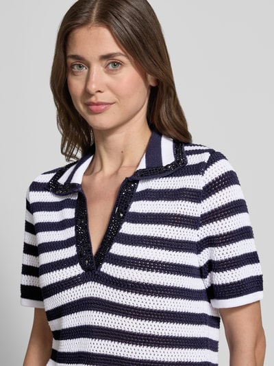 Frauenmodel trägt Regular Fit Poloshirt in Strick-Optik von monari, reine Baumwolle, halbarm, Ziersteinbesatz, semitransparent, Nahaufnahme Oberkörper.