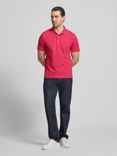 Männermodel trägt Slim Fit Poloshirt aus Baumwoll-Mix Modell 'Pete' von BRAX in leuchtendem Rot, Polokragen, Ganzkörperansicht von vorne. Rückenlänge bei Größe M 71 cm.