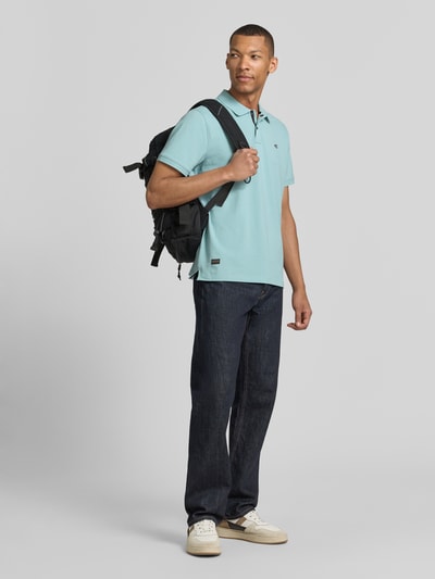 Männermodel trägt Regular Fit Poloshirt in unifarbenem Design van camel active, mix van katoen en elastaan, knoopsluiting, logo, ruglengte bij maat M 70 cm, effen lichtblauw, donkere jeans, lichte schoenen, Ganzkörperansicht van voren.