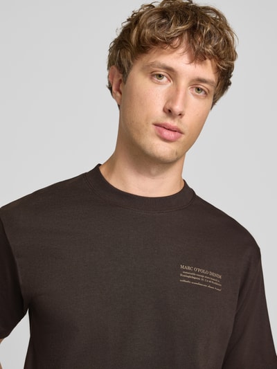 Männermodel trägt Relaxed Fit T-Shirt aus reiner Baumwolle von Marc O'Polo DENIM in Dunkelbraun, glatte Oberfläche, Nahaufnahme Oberkörper.