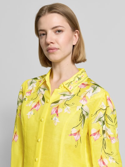 Frauenmodel trägt Bluse aus Leinen-Mix mit Knopfleiste von Marc Cain in leuchtendem Gelb, florales Muster, Hemdblusenkragen, Nahaufnahme Oberkörper.