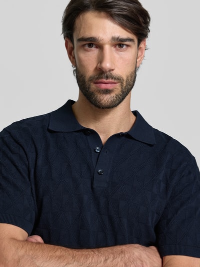 Männermodel trägt Regular Fit Poloshirt mit Strukturmuster von MCNEAL in Dunkelblau, reine Baumwolle, Strick-Optik, Nahaufnahme Oberkörper.