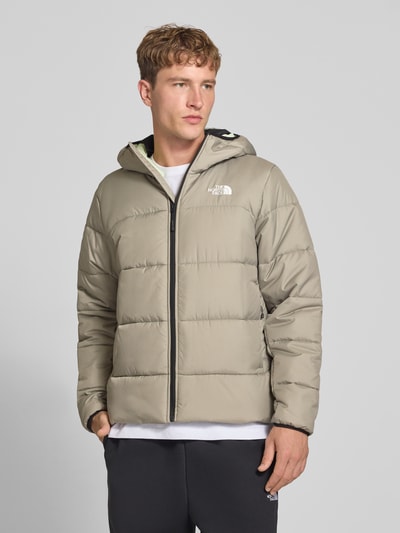 Männermodel trägt Regular Fit Jacke in Stepp-Optik von The North Face in Beige mit Kapuze und Logo-Print, Nahaufnahme Oberkörper. Rückenlänge 68 cm, Schulterbreite 46 cm, Brustweite 55 cm, Ärmellänge 70 cm.