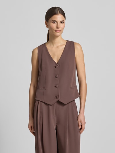 Kobiece modelka nosi Regular Fit Weste mit V-Ausschnitt von Christian Berg Cocktail z elastyczną mieszanką materiałów, krój regular fit, dekolt w serek, pełna listwa guzikowa, długość tyłu w rozmiarze 36: 46 cm, kolor matowy brąz, gładka tekstura, widok całej sylwetki z przodu.