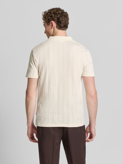 Męski model nosi Regular Fit Poloshirt in Jaquard-Strick od Lindbergh, czysta bawełna, krój regular fit, wzór żakardowy, kołnierzyk polo, dekolt w serek, detal z logo, długość tyłu w rozmiarze M: 73 cm, kolor jasny, geometryczny wzór, tekstura dzianinowa, widok całej sylwetki z tyłu.