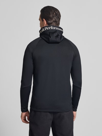 Männermodel trägt Slim Fit Jacke mit Logo-Print Modell 'Rider' von Peak Performance, Elastischer-Material-Mix, Stehkragen, Ganzkörperansicht Rückansicht.