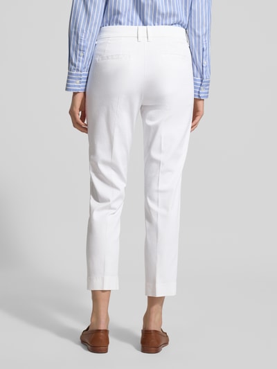 Frauenmodel trägt weiße Straight Fit Stoffhose mit Lyocell-Anteil Modell 'Mara' von BRAX, elastischer Baumwoll-Mix, Bügelfalten, verkürzte Passform, Eingriff- und Gesäßtaschen, Knopf- und Reißverschluss, Ganzkörperansicht Rückansicht.