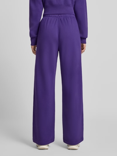 Frauenmodel trägt Wide Leg Sweathose aus Baumwoll-Mix mit Logo-Stitching von Polo Ralph Lauren in Lila, glatte Textur, Ganzkörperansicht Rückansicht. Damen Sweathose von Polo Ralph Lauren