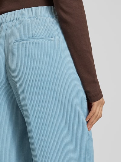 Frauenmodel trägt hellblaue Stoffhose mit elastischem Bund Modell 'Cevil' von Someday aus Cord, Material-Mix mit Stretch-Anteil, Nahaufnahme Rückansicht.