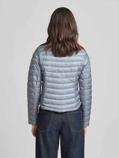 Frauenmodel trägt Steppjacke mit Stehkragen von Gil Bret, Körpernahe Passform, silbergraue Farbe, Reißverschlusstaschen, Ganzkörperansicht Rückansicht, Rückenlänge bei Größe 36: 56 cm, Schulterbreite: 39 cm, Brustweite: 47 cm, Ärmellänge: 66 cm.