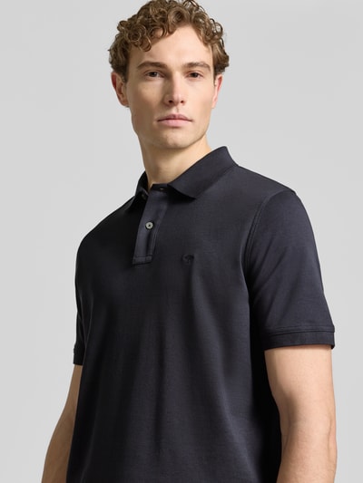 Männermodel trägt Regular Fit Poloshirt mit Logo-Stitching von Fynch-Hatton, reine Baumwolle, dunkelblau, Nahaufnahme Oberkörper.