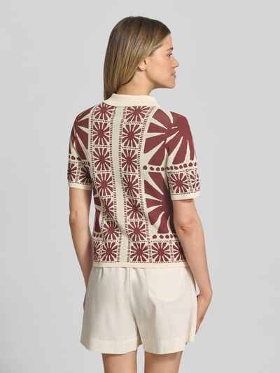 Frauenmodel trägt Strickshirt mit Umlegekragen Modell 'GABERA' von SUNCOO PARIS aus Viskose-Mix, Regular-Fit, Rückenlänge 55 cm, Ärmellänge 26 cm, cremefarben mit braunem Muster, Kurzarm, Knopfverschluss, Ganzkörperansicht Rückansicht.