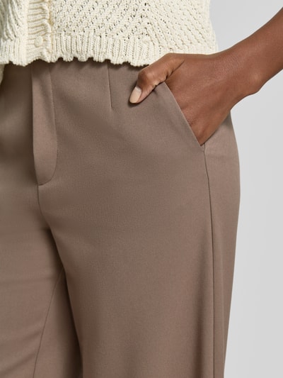 Frauenmodel trägt High Waist Hose Modell 'VARONE' von Vila in Beige mit Wide Leg, glatte Textur, Material-Mix mit Viskose-Anteil, Nahaufnahme Oberkörper.