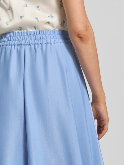 Frauenmodel trägt ausgestellten unifarbenen Ausgestellter Midi-Rock aus Viskose-Mix Modell 'MIRA' von Vero Moda mit Volant-Saum in Satin-Optik, elastischer Bund, Nahaufnahme Hüfte und Hand, Ganzkörperansicht Rückansicht.