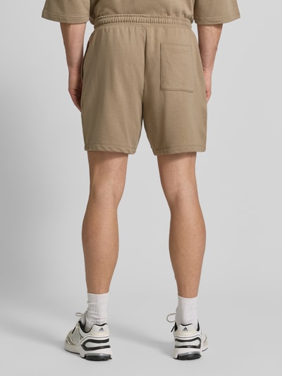 Männermodel trägt Straight Fit Shorts mit Logo-Stitching Modell 'Arch' von GAP, beiger Baumwoll-Mix, elastischer Bund, Ganzkörperansicht Rückansicht