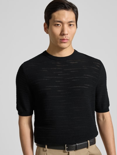 Männermodel trägt Strickshirt aus Baumwolle von Antony Morato in Schwarz mit Gerader-Schnitt, Rundhalsausschnitt, Gerippte-Abschlüsse, Halbarm, Nahaufnahme Oberkörper.