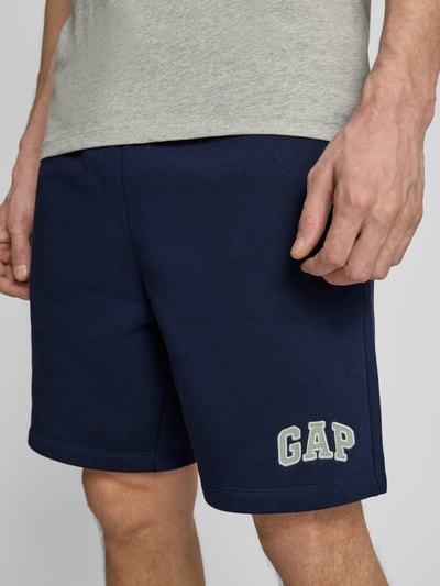 Männermodel trägt Sweatshorts mit elastischem Bund von GAP aus Baumwoll-Mix, Relaxed-Fit, Logo, dunkles Blau, Nahaufnahme Oberschenkel.