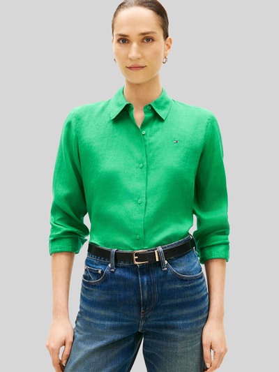 Frauenmodel trägt Relaxed Fit Langarmbluse aus reinem Leinen von Tommy Hilfiger, Optik: Unifarben in Grün, Hemdkragen, Logo-Stitching, einreihige Knopfleiste, langarm mit Manschette, abgerundeter Rumpfabschluss, Materialverarbeitung: Flammgarn, Material: reines Leinen, Nahaufnahme Oberkörper.