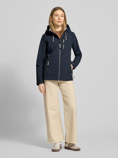 Frauenmodel trägt dunkelblaue Damen Jacke mit Kapuze, Reißverschluss und Reißverschlusstaschen, Slim-Fit, Modell 'GS111' von G.I.G.A. DX, Rückenlänge 69 cm, Schulterbreite 39 cm, Brustweite 44 cm, Ärmellänge 65 cm, 10.000 mm Wassersäule, Ganzkörperansicht von vorne.
