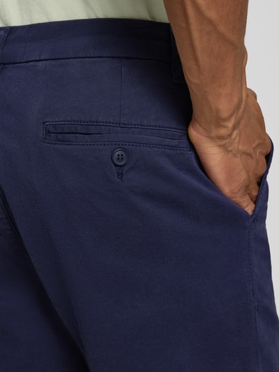 Männermodel trägt Regular Fit Chinoshorts aus Baumwoll-Mix Modell 'CHINO' von Armedangels in Dunkelblau, Detailaufnahme Rückansicht.