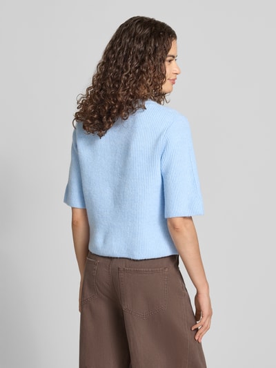 Frauenmodel trägt Boxy Fit Strickjacke aus Rippstrick Modell 'SILLY' von PIECES in Hellblau-Melange, kurzarm, Rückansicht, Ganzkörperansicht.
