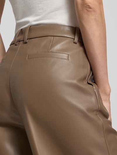 Männermodel trägt spodnie z szerokimi nogawkami z materiału skóropodobnego, model 'Wessy' od STAND STUDIO, beżowy kolor, długość wewnętrzna nogawki 80 cm, szerokość w rozmiarze 36: 38 cm, szwy wzdłużne, detaliczne zbliżenie tylnej części.