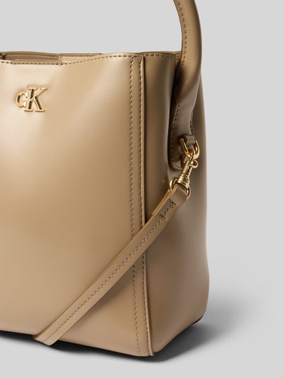 Produktfoto, torebka z uchwytem z mieszanki materiałów, główna przegroda z zamkiem błyskawicznym, detal z logo, pasek na ramię, CK Calvin Klein, szerokość 22 cm, długość 22 cm, głębokość 14 cm, długość paska na ramię 122 cm, neutralny beżowy kolor, gładka faktura.