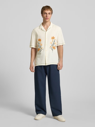 Męski model nosi Relaxed Fit Freizeithemd mit Motiv-Stitching od REVIEW, koszula bawełniana z motywem, całkowity widok z przodu. Długość tyłu w rozmiarze M: 72 cm, szerokość ramion w rozmiarze M: 45 cm, długość rękawa w rozmiarze M: 30 cm. Kolory: kremowy, pomarańczowy haft, faktura lekko wzorzysta.