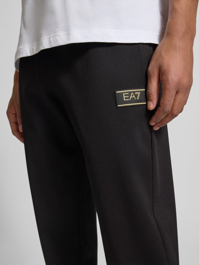 Männermodel trägt Sweatpants mit elastischem Bund und Label-Patch von EA7 Emporio Armani, materiaalmix met viscose, relaxed fit, labelpatch, detailaufnahme.
