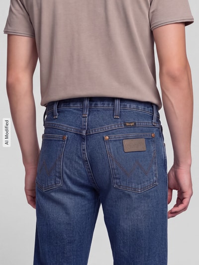 Männermodel trägt Regular Fit Bootcut Jeans aus reiner Baumwolle Modell '13MWZ Cowboy' von Wrangler in Blau, Ganzkörperansicht Rückansicht, Herren Straight Fit Jeans von Wrangler, KI-modifiziertes Bild.
