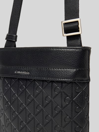 Produktfoto, Handtasche mit Label-Detail und Schulterriemen von Calvin Klein für Herren, schwarzer Allover-Look, Struktur, Hauptfach mit Reißverschluss, Breite 21 cm, Länge 19 cm, Tiefe 3 cm, Schulterriemen 73 cm