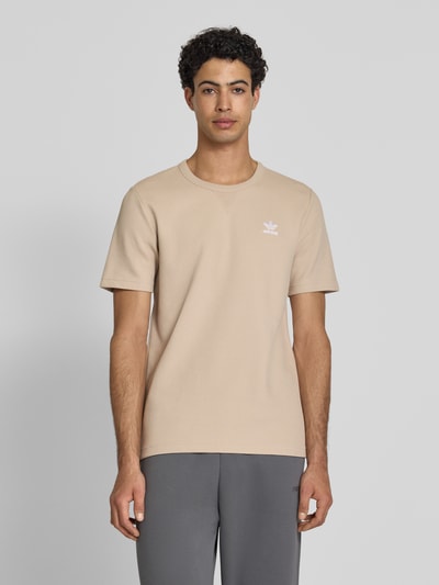 Męski model nosi Regular Fit T-Shirt mit Baumwoll-Anteil von adidas Originals, efekt: jednolity kolor, krój regular fit, wzór: faktura wafla, okrągły dekolt, wyhaftowane logo, krótki rękaw; Ganzkörperansicht z przodu.