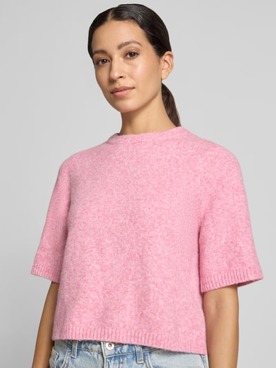 Kobiece model prezentuje sweter oversized z dodatkiem wełny model 'BOOM' od VERO MODA, różowy, miękka faktura, zbliżenie na górę ciała.