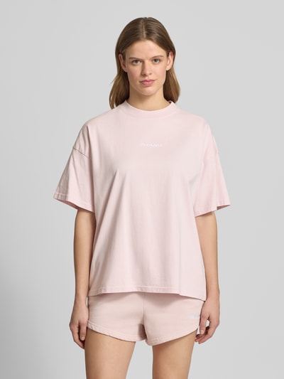 Frauenmodel trägt Oversized Fit Damen T-Shirt aus Reine Baumwolle mit Rundhalsausschnitt und Label-Stitching, Modell 'BRACY' von Pegador in zartem Rosaton, glatte Oberfläche, Rückenlänge bei Größe S: 63 cm, Ganzkörperansicht von vorne.