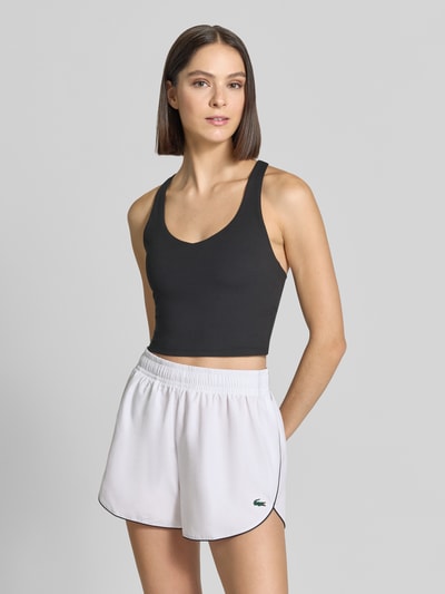 Kobiece model prezentuje Cropped Top mit integrierten Cups od Fabletics, czarny kolor, okrągły dekolt, krój slim fit, długość pleców w rozmiarze S: 36 cm, cała sylwetka z przodu.