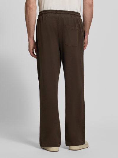 Männermodel trägt braune Regular Fit Sweathose aus Baumwoll-Modal-Mix von Tommy Hilfiger, glatte Textur, Ganzkörperansicht Rückansicht. Herren Sweathose von Tommy Hilfiger