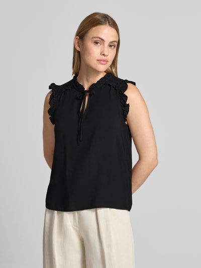 Kobiece modelka nosi Regular Fit Blusentop aus reiner Viskose Modell 'ALBA' od Vero Moda, czarny, bez rękawów, z falbankami i wiązaniem, widok z przodu na górną część ciała.