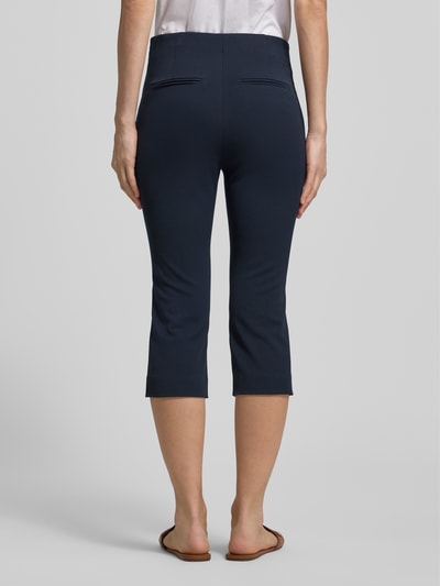 Frauenmodel trägt Caprihose mit Längsnähten von Rich & Royal in Dunkelblau, Slim Fit, Reißverschluss, Gesäßtaschen, Ganzkörperansicht Rückansicht.