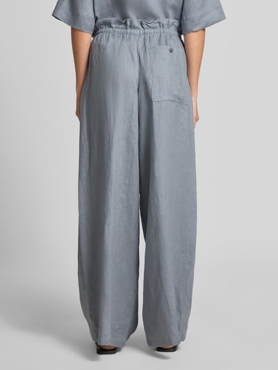 Männermodel trägt Wide Leg Leinenhose Modell 'DWINDLE' von Drykorn, szary len, elastyczny pas, sznurek, Ganzkörperansicht Rückansicht, kontekst: damskie spodnie lniane, szerokość w rozmiarze 27/34: 38 cm, długość nogawki wewnętrznej w rozmiarze 27/34: 83 cm