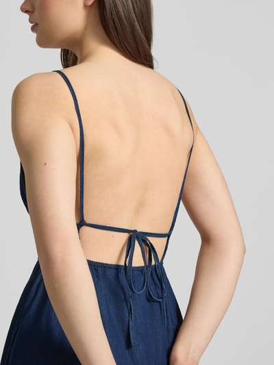 Frauenmodel trägt Jeanskleid mit rückseitiger Schnürung Modell 'DEBBY CHAMBREY' von JJXX aus reiner Baumwolle, Nahaufnahme Rückenansicht.