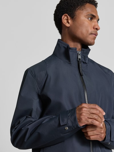Männermodel trägt kurtka funkcyjna Regular Fit Funktionsjacke aus wasserdichtem Material Modell 'LUCCA' von Strellson, jednokolorowy, stójka, zamek błyskawiczny, aplikacja z logo z metalu, długi rękaw z patką, wiatroszczelny, kieszenie boczne na zamek, Nahaufnahme górnej części ciała.