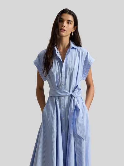 Frauenmodel trägt Tailliertes Hemdblusenkleid aus reiner Baumwolle von Polo Ralph Lauren in Hellblau, unifarben, mit Taillengürtel und Logo-Stitching, Maxi-Länge, Knopfleiste, kurzarm, seitliche Eingrifftaschen, glatte Textur, Ganzkörperansicht von vorne.