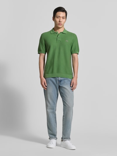 Männermodel trägt Regular Fit Poloshirt aus reiner Baumwolle von Lacoste, Optik: Unifarben, Logo-Stitching, Ganzkörperansicht von vorne.