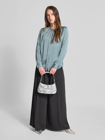 Frauenmodel trägt Schultertasche mit Raffungen von Jake*s Cocktail aus silbernem Satin, kurze Henkel, Ganzkörperansicht von vorne.
