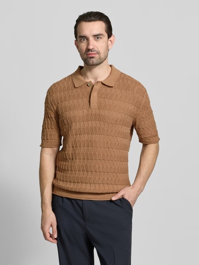 Männermodel trägt Regular Fit Poloshirt mit Strukturmuster von Scotch & Soda in Braun, reine Baumwolle, Polokragen, verdeckte Knopfleiste, Ganzkörperansicht von vorne.
