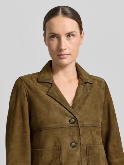 Vrouwenmodel draagt Lederblazer met opgestikte steekzakken van Stefanel in olijfgroen leer, recht model, reverskraag, knoopsluiting, Nahaufnahme Oberkörper, ruglengte maat S 52 cm, borstwijdte 48 cm, mouwlengte 59 cm.
